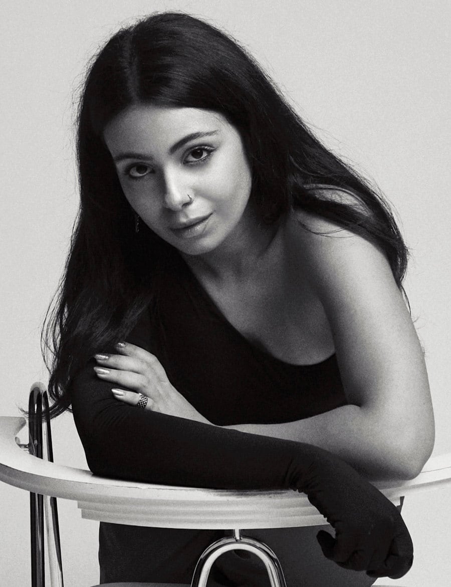 Black-and-white studio portrait of Valeria Manasaryan leaning over the back of a chair, wearing a long black glove